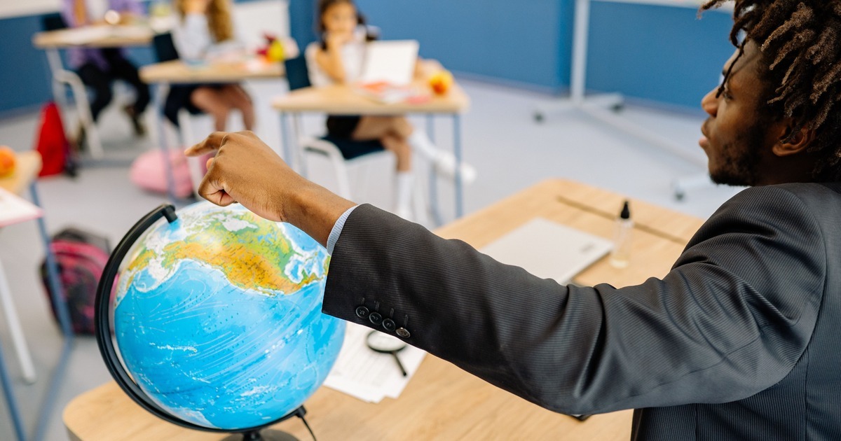 Teacher pointing to a globe during a classroom lesson.